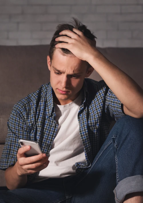 Young man looking stressed on his phone.